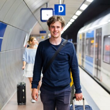 Person mit Gepäck geht entlang des Bahnsteigs der Flughafen/Messe Station. 