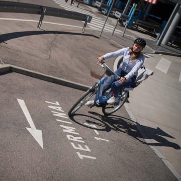 Anreise mit dem Fahrrad zum Flughafen Stuttgart Frau fährt mit dem Fahrrad auf ausgeschildertem Weg Richtung Terminal am Flughafen Stuttgart
