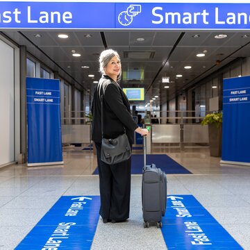 Person mit Gepäck steht vor dem Eingang zur Fast Lane und Smart Lane am Flughafen Stuttgart. 