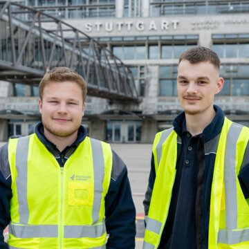 Zwei Auszubildende Mechatroniker in Warnwesten stehen auf dem Vorfeld.