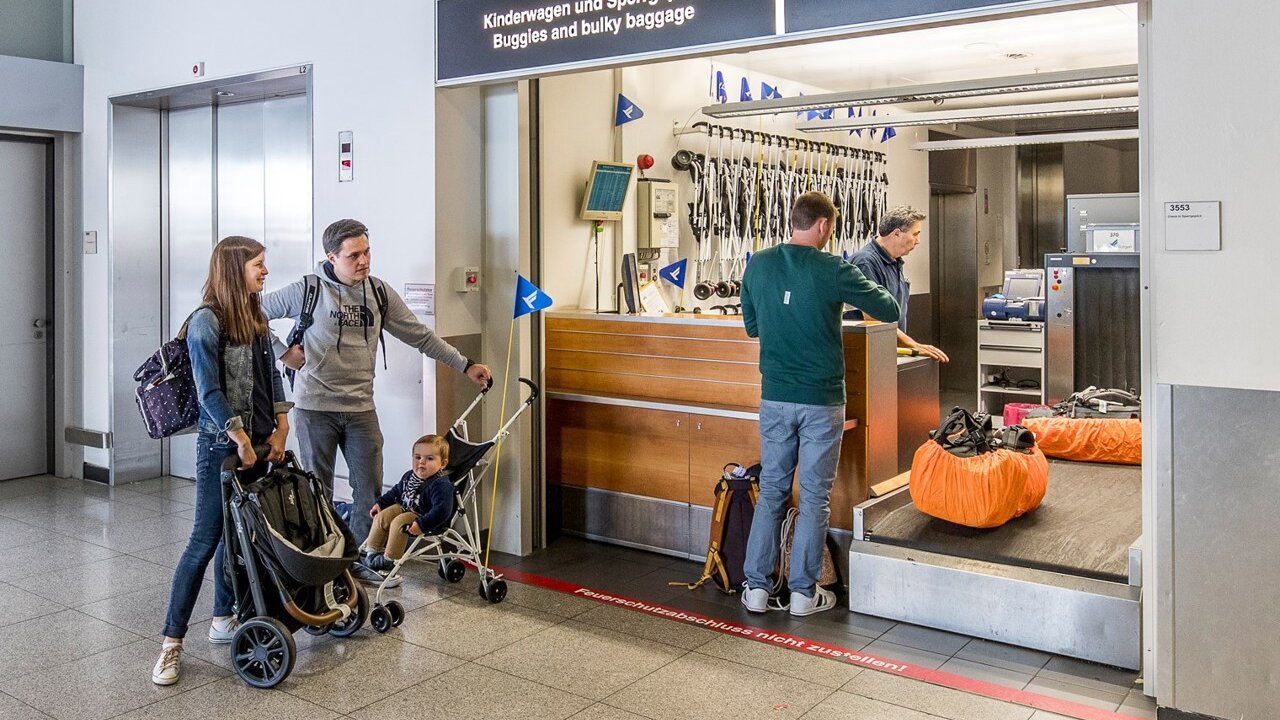 Familie im Flughafen Stuttgart gibt Kinderwagen und Sperrgepäck am Schalter ab.