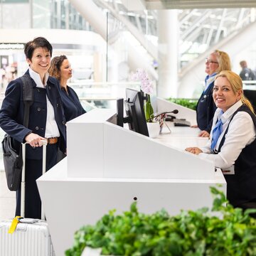 Reisende erhält Informationen an einem Informationsschalter im Flughafen Stuttgart.