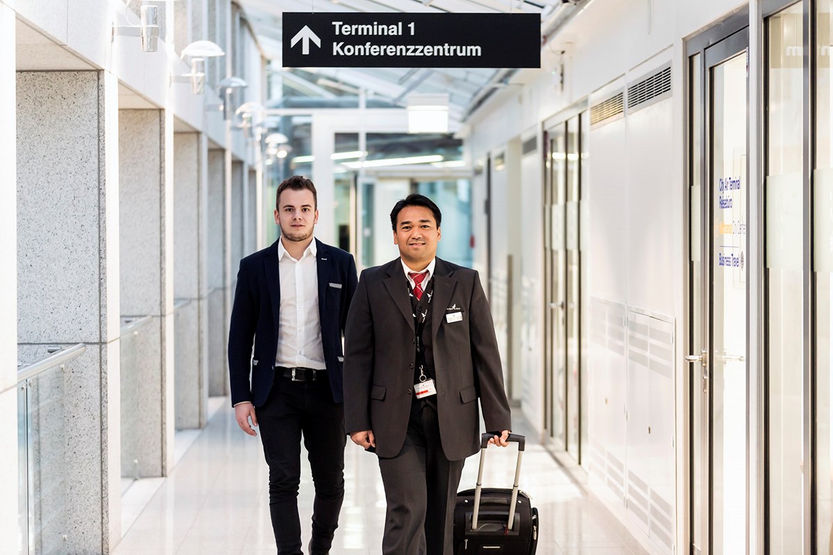 Mitarbeiter begleitet VIP Gast durch das Terminal und trägt seinen Koffer