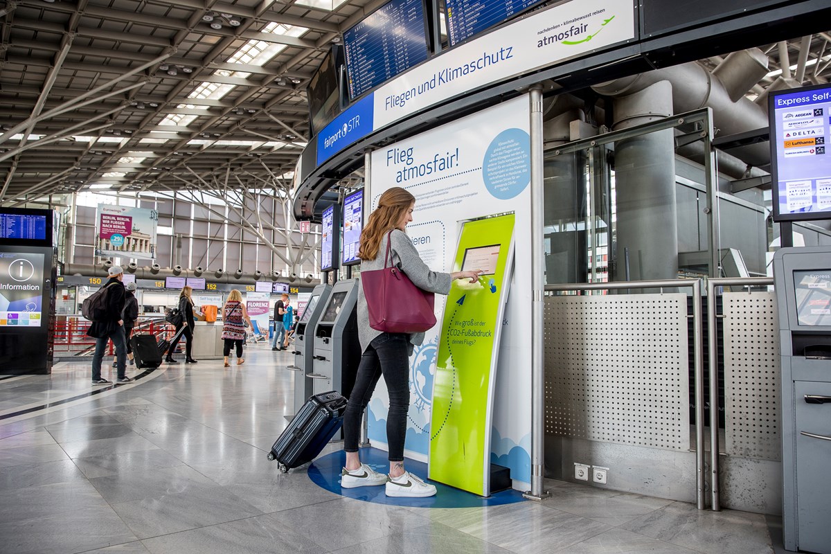 Eine Passagierin berechnet die Emissionen ihres Fluges am Kompensations-Schalter im Terminal.